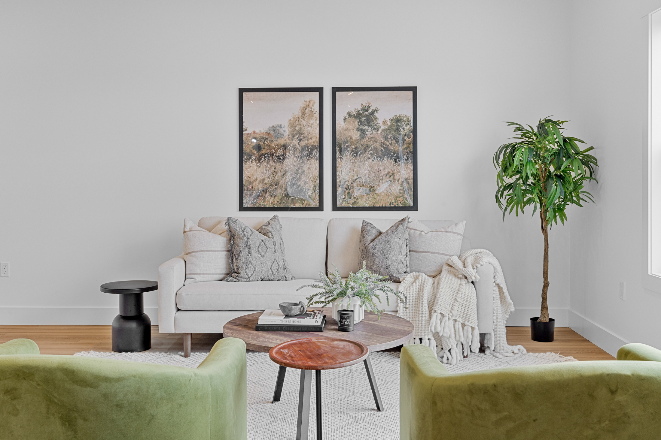 The living room of a condo for sale in PEI which is perfectly staged with two green chairs a couch and a round coffee table
